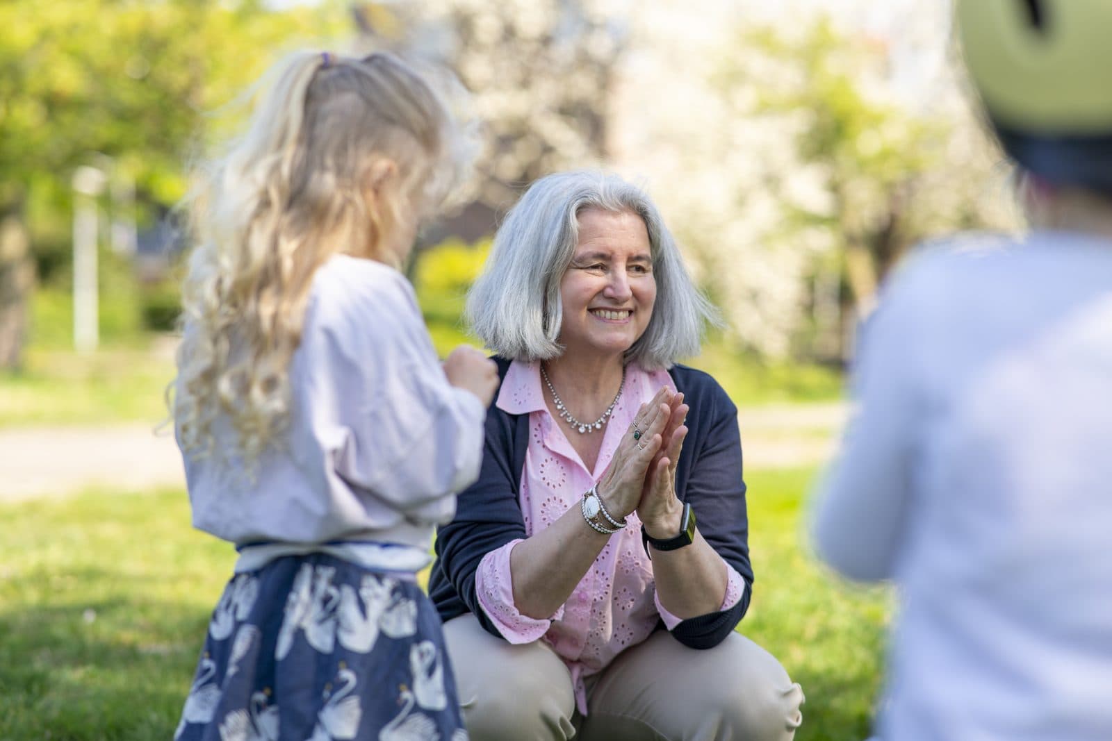 Een gastouder zit op ooghoogte met een klein meisje, klaar om te knuffelen